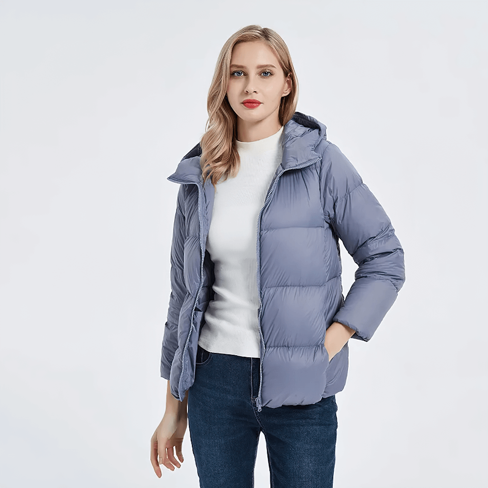 Woman wearing slim-fit duck down jacket with hood, pockets, and full sleeves in light blue. Perfect for chilly weather style.