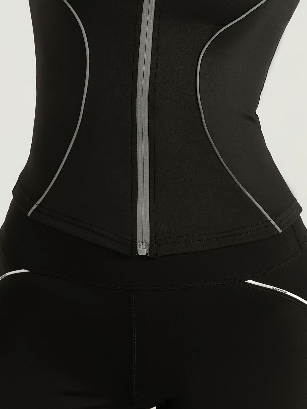 Close-up of women's slim fit sports jacket with full zip and reflective details, ideal for workouts.