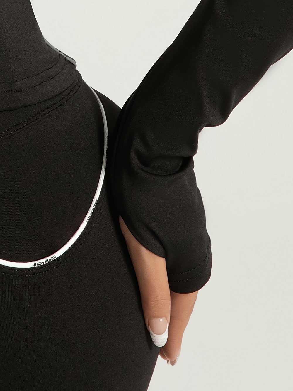 Close-up of black slim fit sports jacket with thumb holes and reflective detail, perfect for women's activewear and workouts.