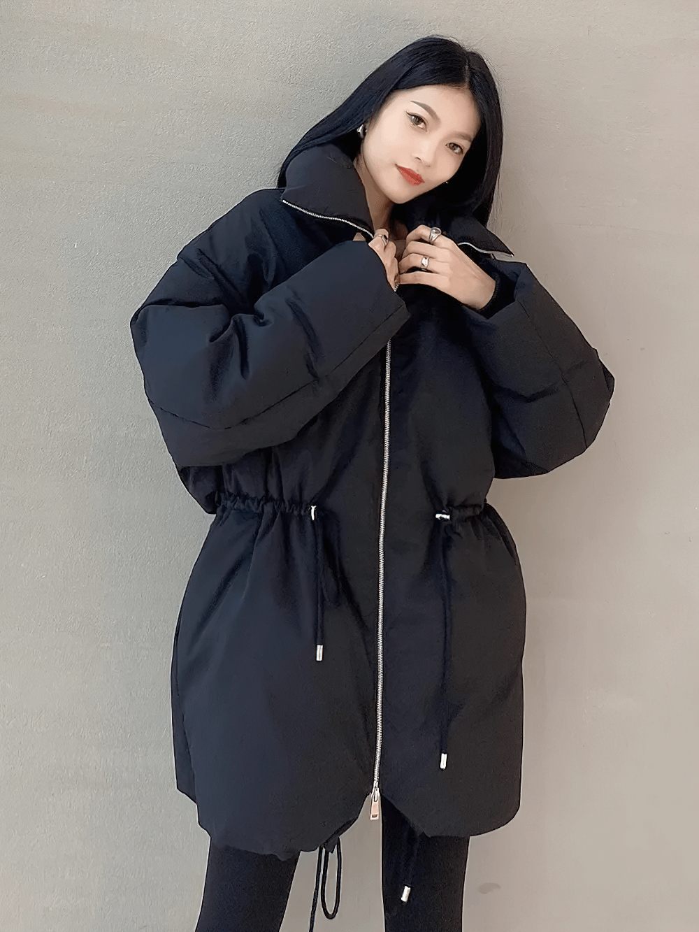 Model wearing a slim fit thick jacket with adjustable waist, showcasing a sleek silhouette and belted closure for winter style.