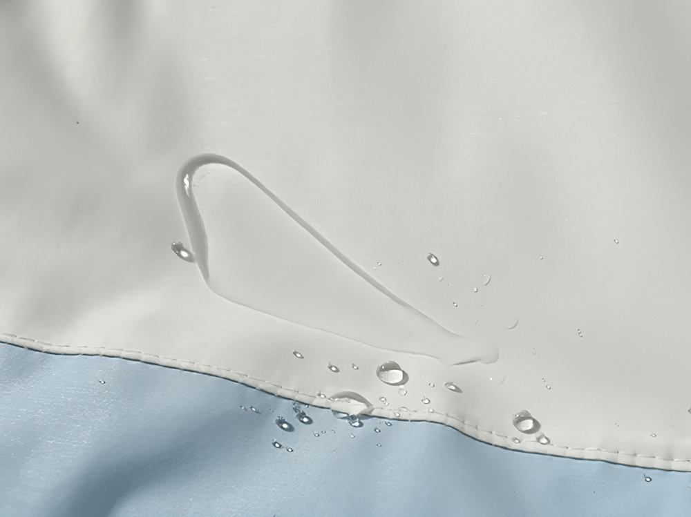 Close-up of waterproof material on snowboard jacket, showcasing water droplet resistance for outdoor sports.