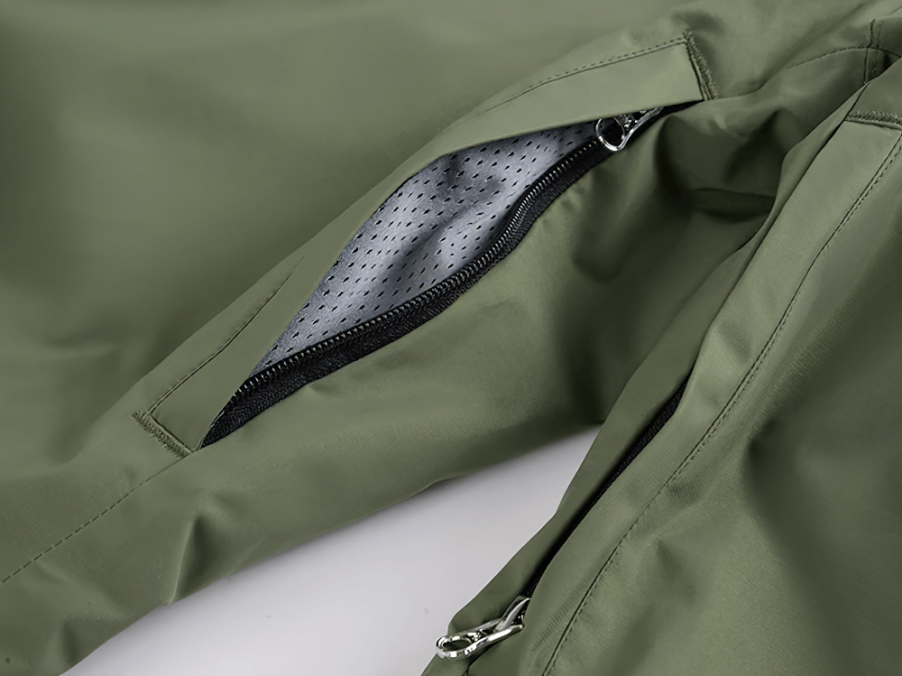 Close-up of a green waterproof snowboard jacket showing a zippered pocket with perforated lining for breathability and style.