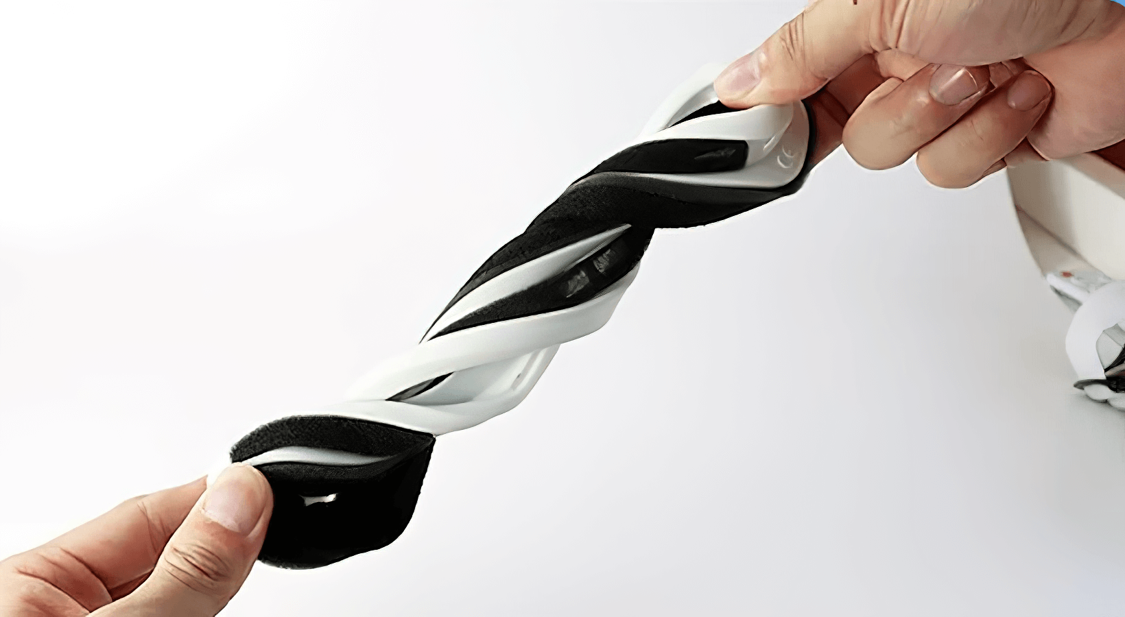 Flexible black and white snowboarding goggles being twisted to show durability.