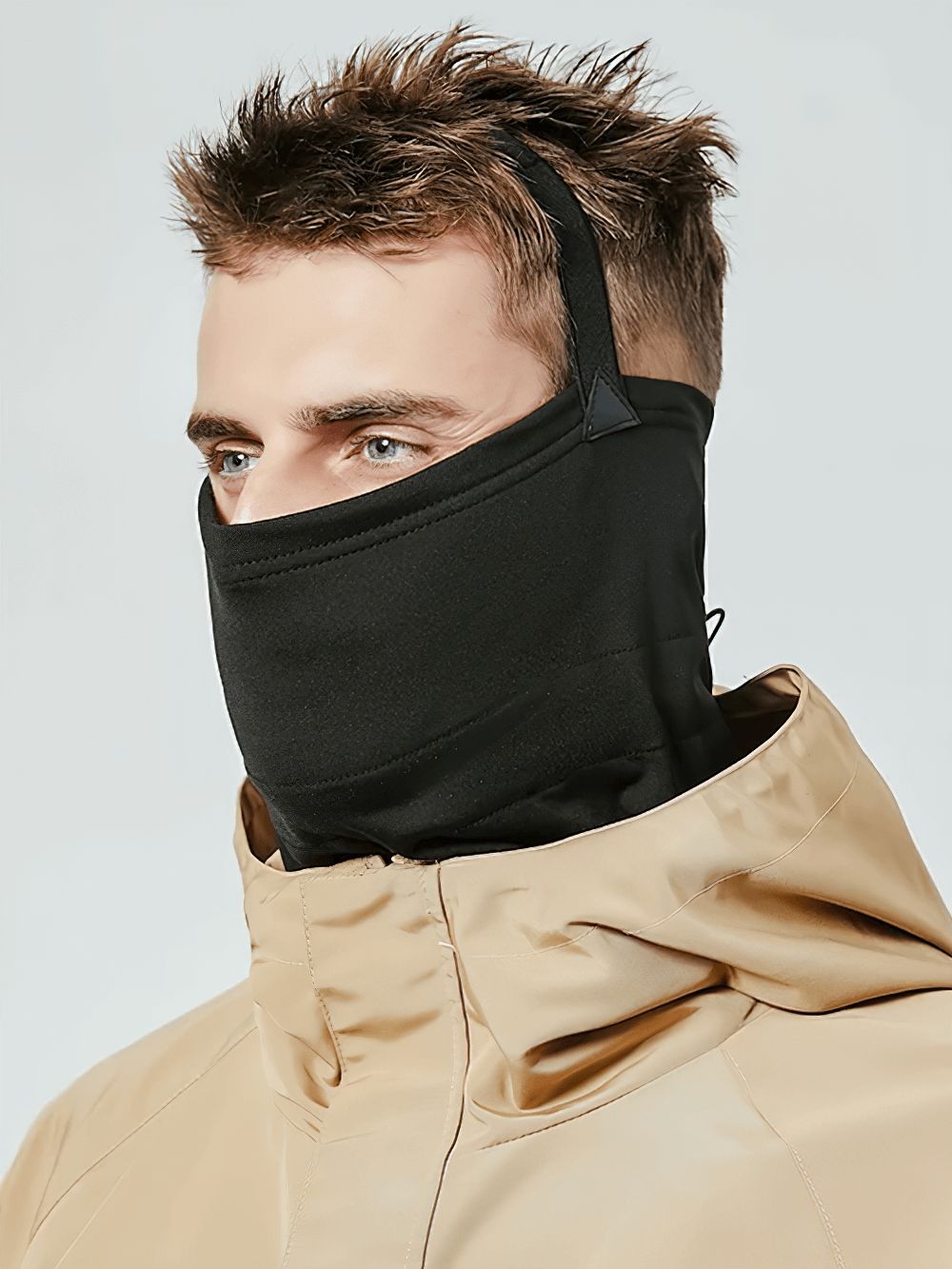 Man wearing snowproof thermal face and neck guard for skiing and snowboarding, with secure elastic drawstring and windproof material.