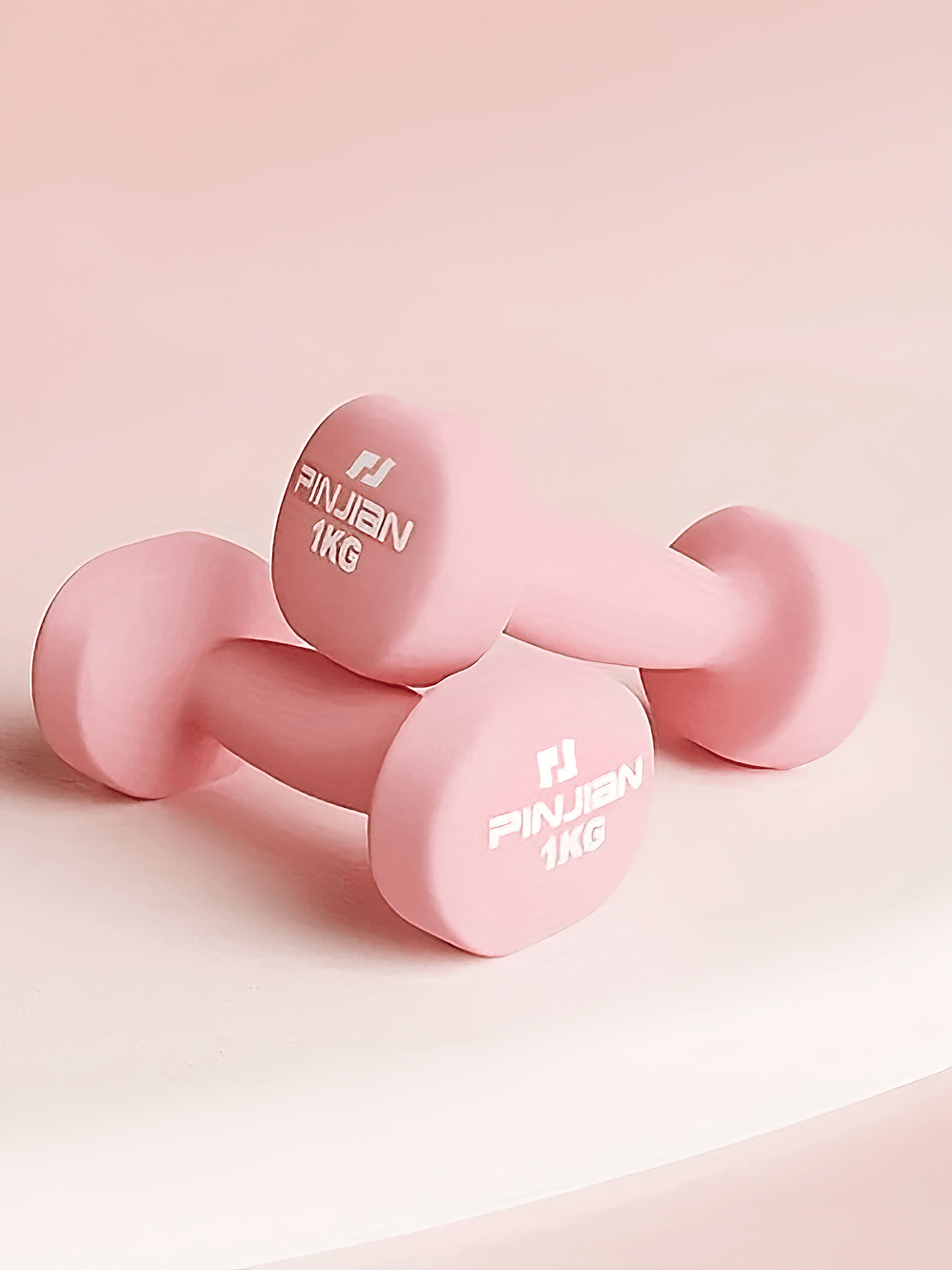 Two soft grip 1kg pink dumbbells with elastic wraps, ideal for home workouts and strength training.