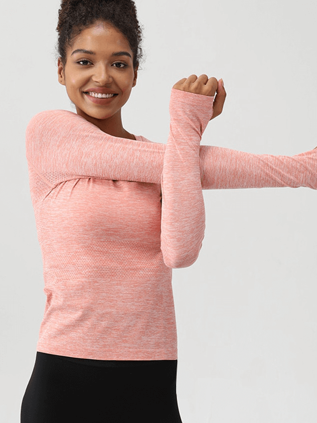 Woman wearing a pink Solid Color Round Neck Yoga Shirt with thumb holes, stretching in breathable, lightweight fabric.