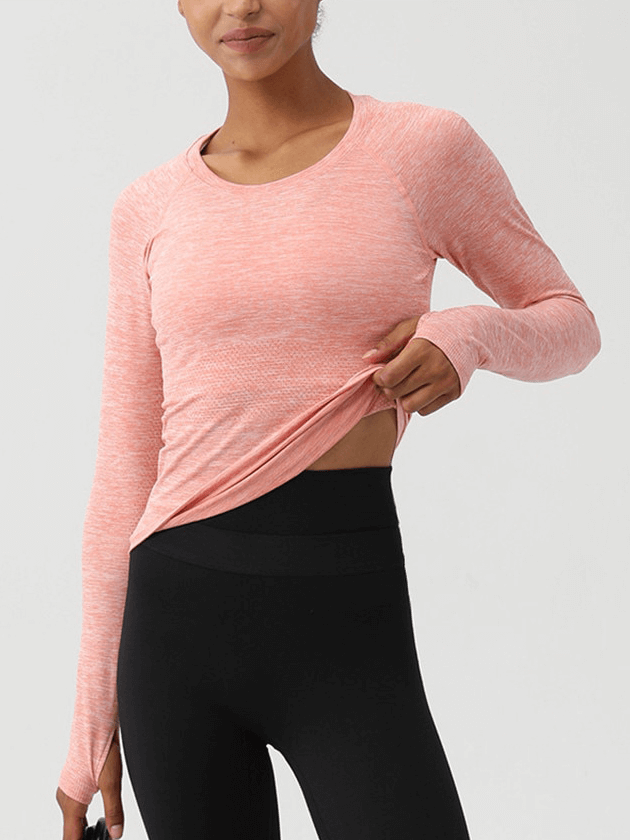 Woman wearing a coral solid color round neck yoga shirt with thumb holes, ideal for fitness and yoga workouts - SF1510.
