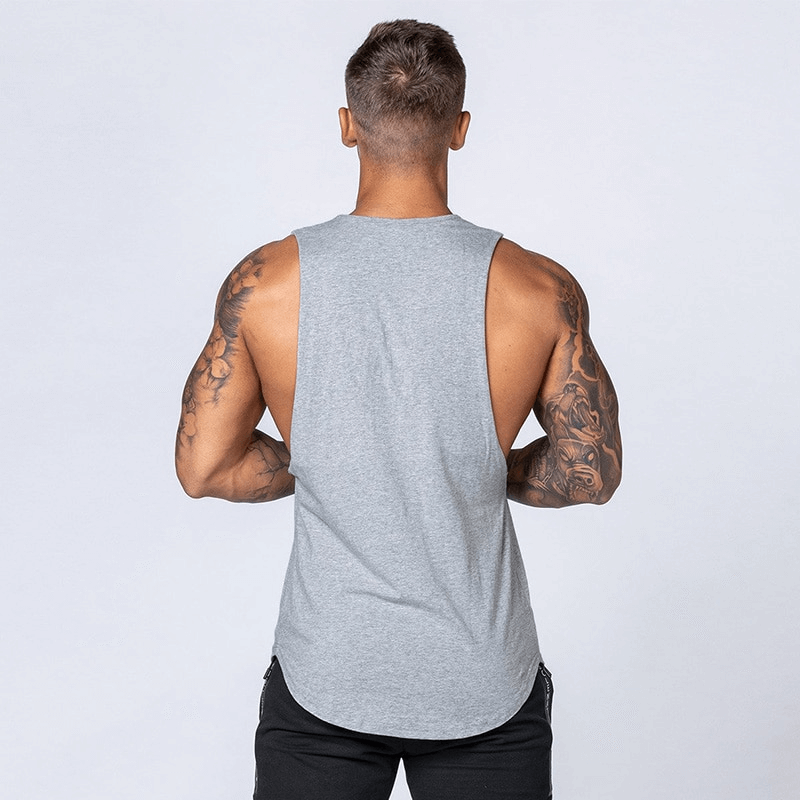 Back view of a man wearing a gray solid cotton fitness tank top, showing muscular arms and a comfortable fit for workouts.