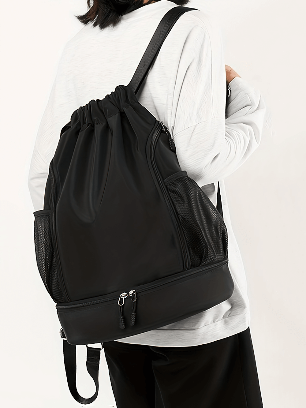 Person wearing spacious black nylon backpack with drawstring and zip closure, ideal for sports and travel, model SF2643.