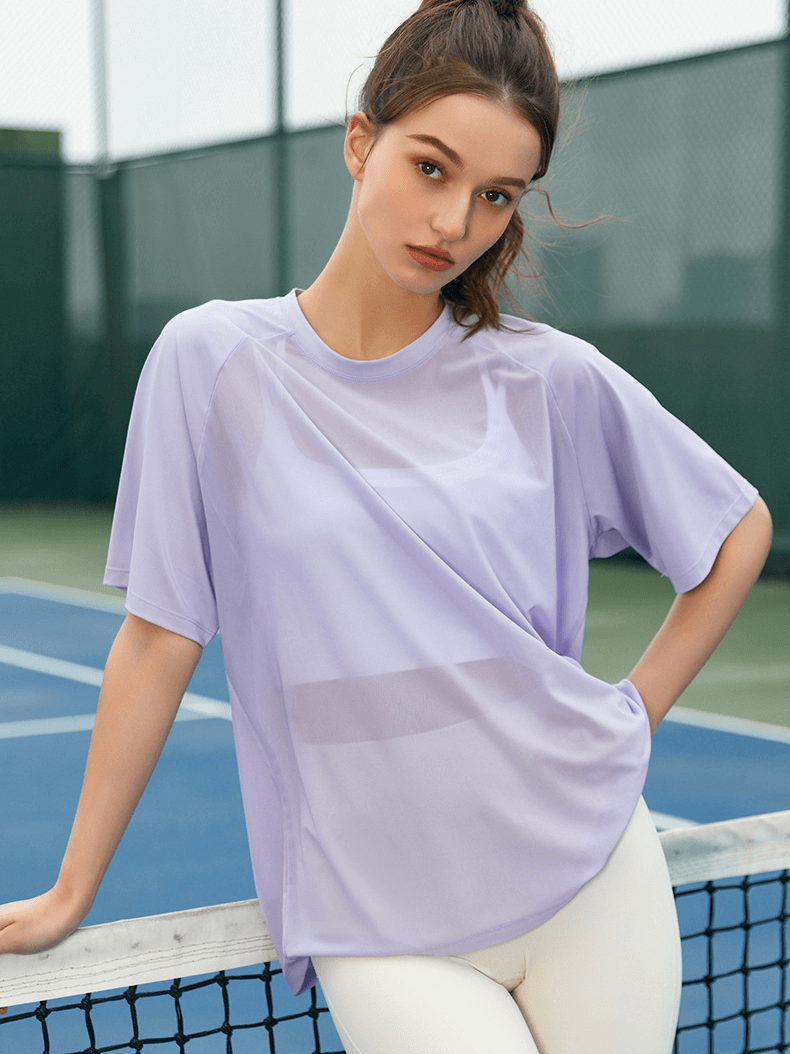 Female model wearing a lavender breathable mesh loose T-shirt on a tennis court, ideal for yoga and quick-drying sportswear.