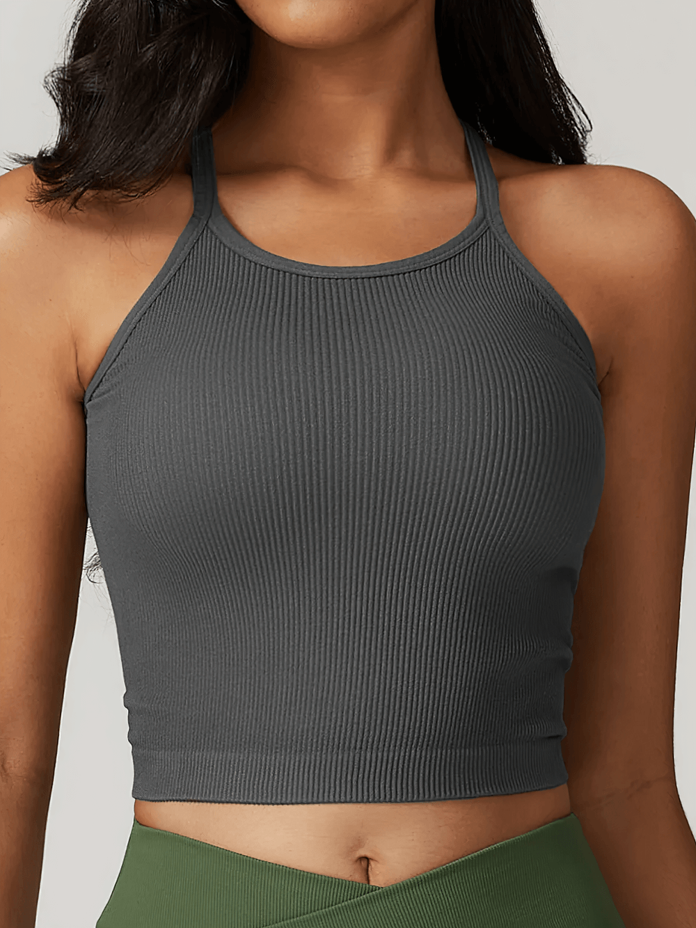 Woman wearing a stylish ribbed racerback tank top, ideal for gym and casual wear, featuring a breathable fabric and sleek fit.