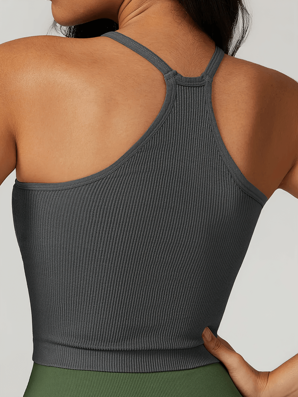 Back view of a woman wearing a grey ribbed racerback tank top, showcasing the breathable fabric and sporty design.