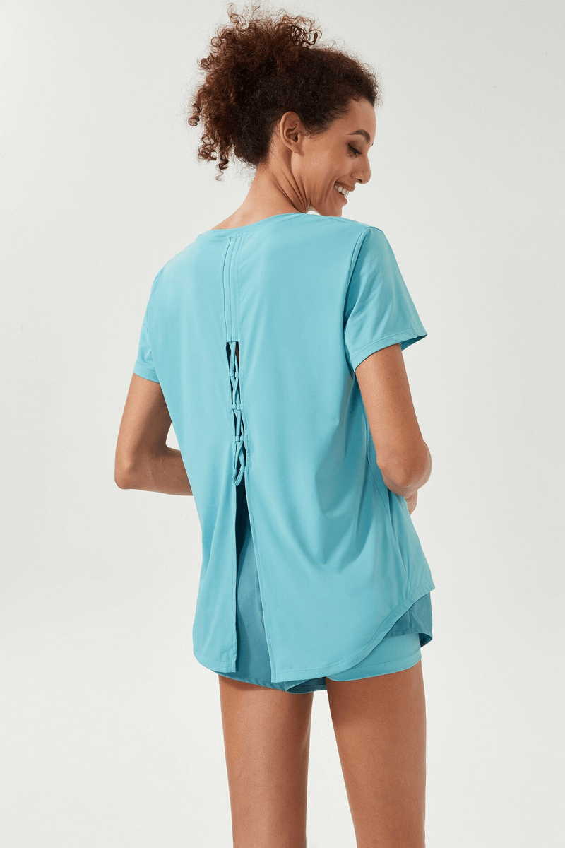 Woman wearing a blue sports breathable t-shirt with slit back, perfect for yoga and workouts. Ideal for fitness and running. Model SF1548.