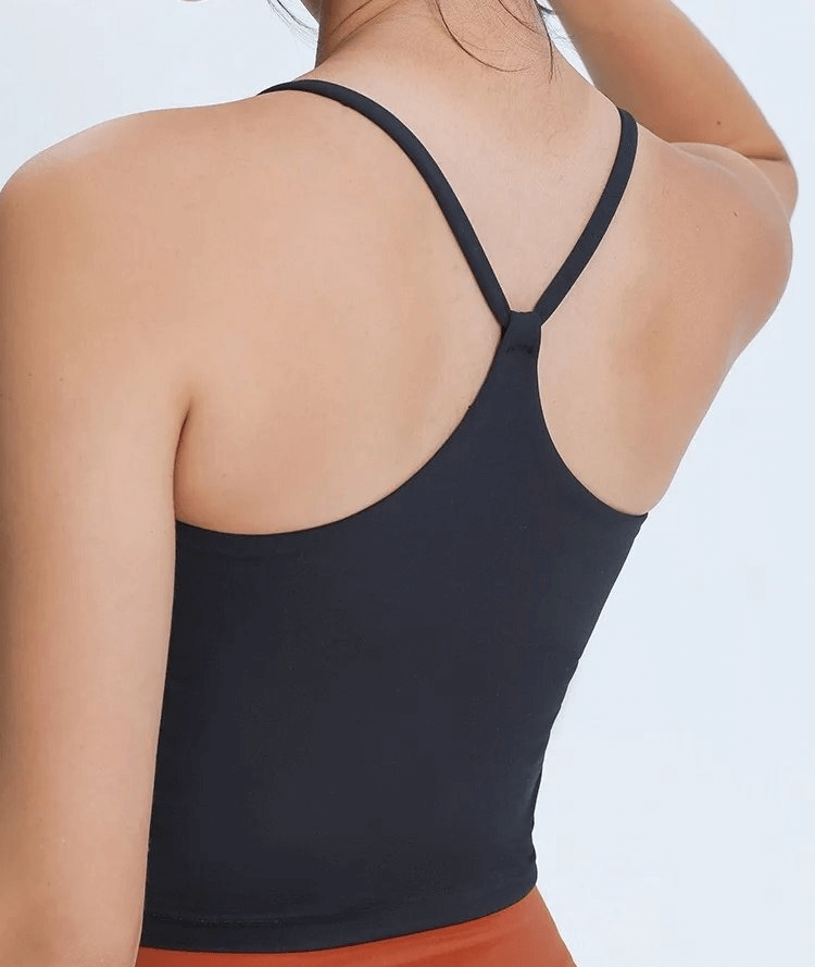 Woman wearing a black sports elastic breathable tank top with adjustable straps, perfect for fitness activities.