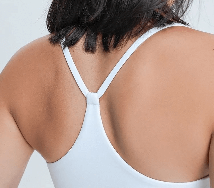 Back view of a woman wearing a white breathable sports tank top with adjustable straps, highlighting fabric detail.