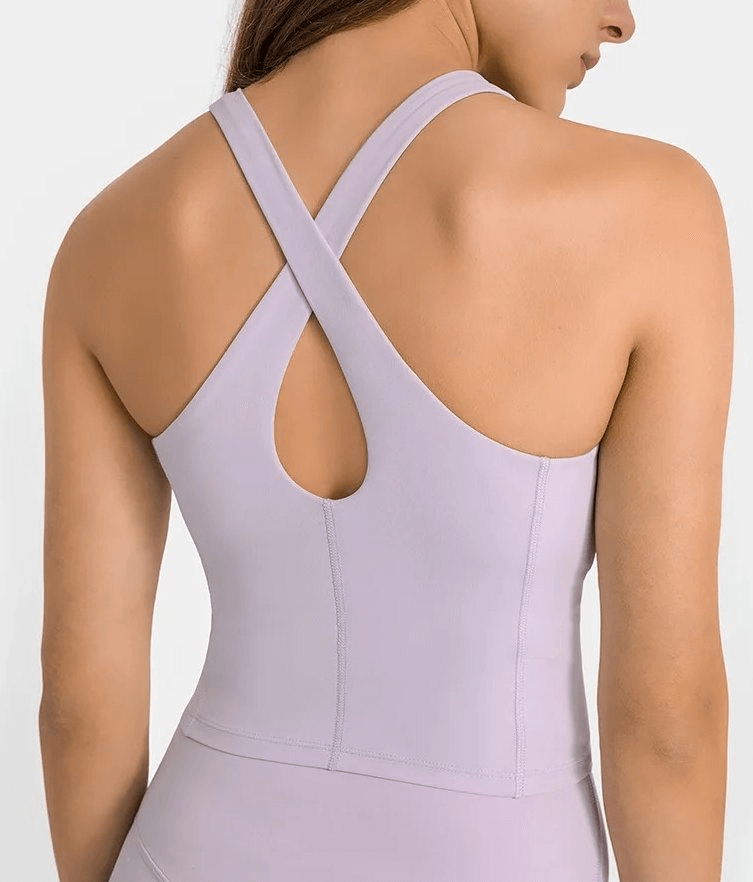 Back view of a woman wearing a lilac sports tank top with a built-in bra, featuring criss-cross straps for fitness and comfort.