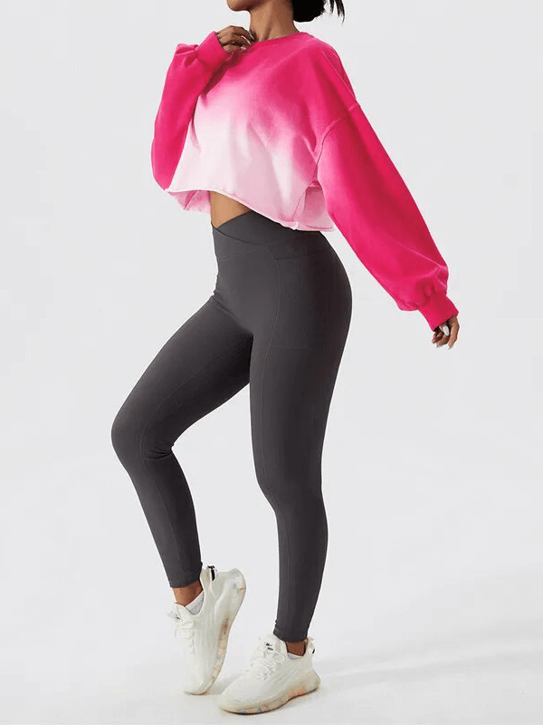 Woman wearing a bright pink gradient long sleeves O-neck crop top and dark leggings, perfect for sporty and active lifestyle.