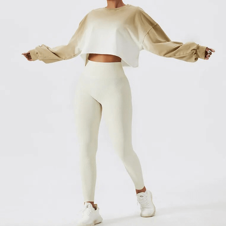 Woman wearing a stylish gradient long sleeve O-neck crop top, perfect for active sports, paired with cream leggings and white sneakers.