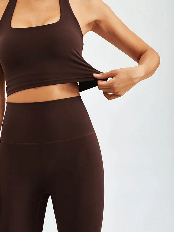 Woman wearing a stylish brown sports fitness set with high waist leggings and sleeveless top, ideal for yoga and workouts.