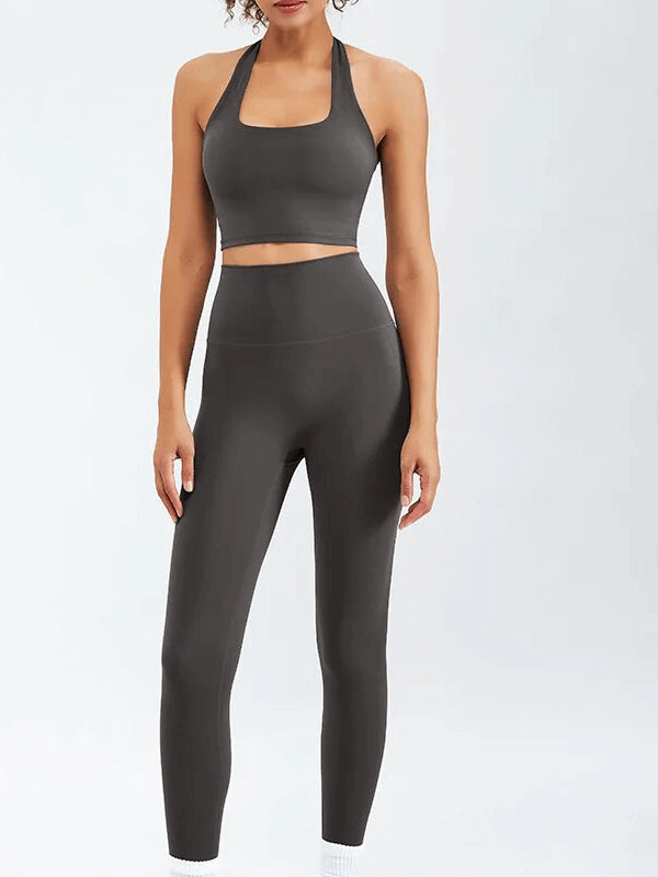 Woman wearing a stylish gray sports fitness set with sleeveless bra and high-waisted leggings, perfect for yoga and running.