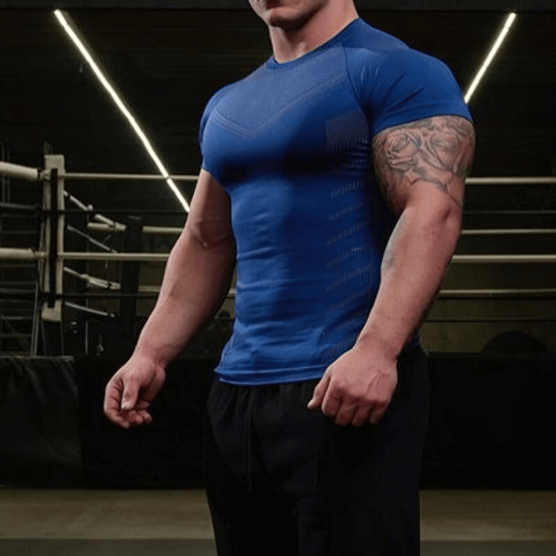 Athletic man wearing blue quick-dry workout t-shirt, spandex material, in a gym setting.