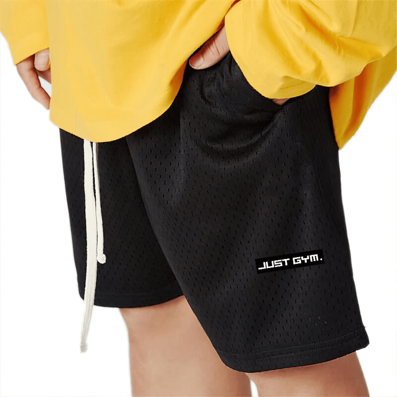 Men's black sports mesh shorts with pocket, featuring breathable fabric, ideal for gym and running. Model wears yellow top.