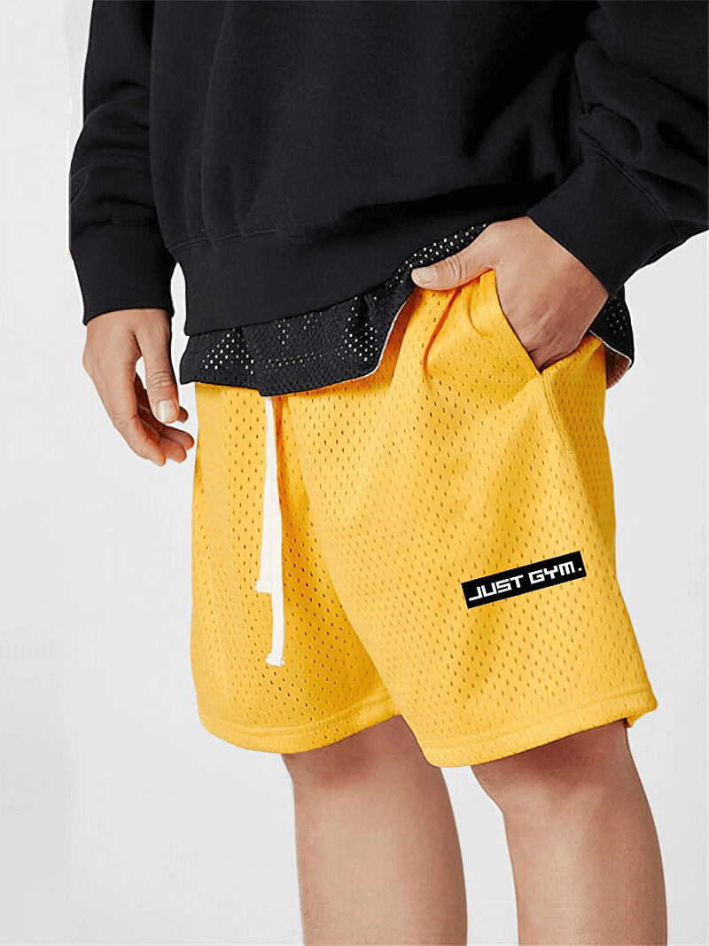 Male model wearing yellow mesh men's running shorts with pockets for gym or sports activities.