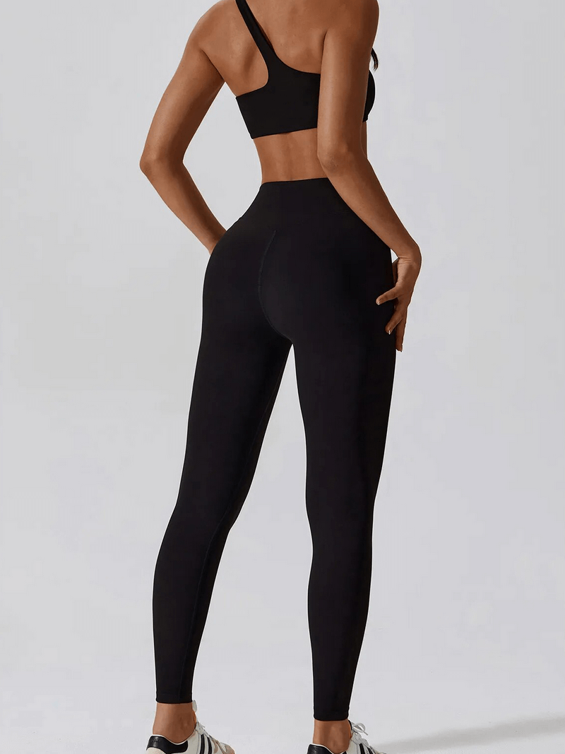 Back view of woman wearing black one-shoulder sports bra and leggings set, showcasing comfortable and stylish activewear for workouts.