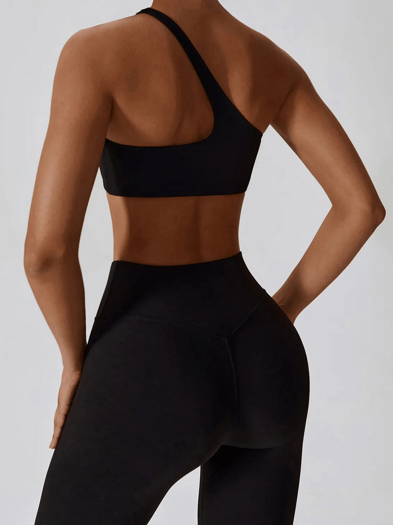 Back view of woman wearing black sports one shoulder push-up bra and leggings SF1697, showcasing breathable nylon fabric and slim fit design.