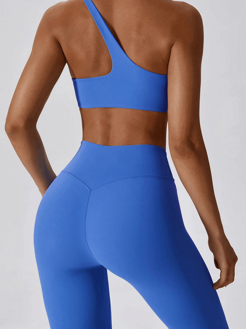 Woman wearing blue one shoulder push-up bra and leggings set, showing a sleek design perfect for exercise and style.