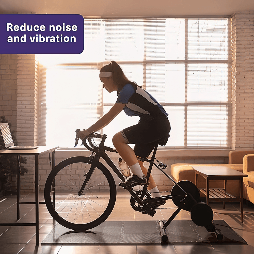 Indoor cyclist using sports protection non-slip gym mat for noise reduction and stability during workout.