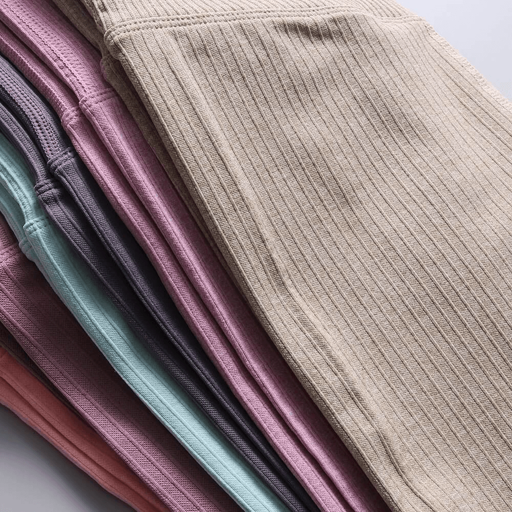 Stack of colorful seamless high waist ribbed leggings for women in beige, pink, and gray shades for yoga or exercise.