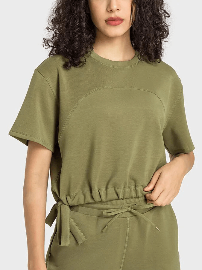 Woman wearing a green sports short sleeves crop T-shirt with adjustable hem, ideal for yoga and running. Breathable, anti-pilling fabric.