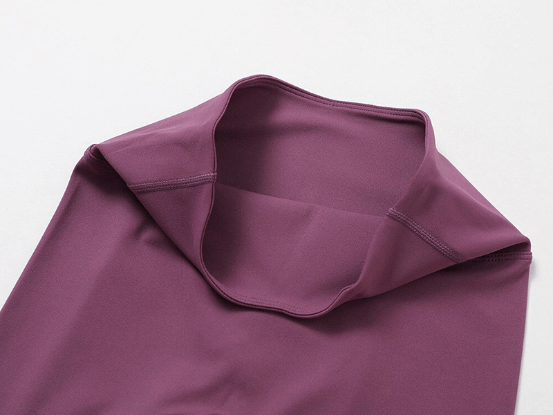 Close-up of maroon sportswear yoga top, showcasing breathable, quick-dry nylon-spandex fabric. Part of a women's yoga set.