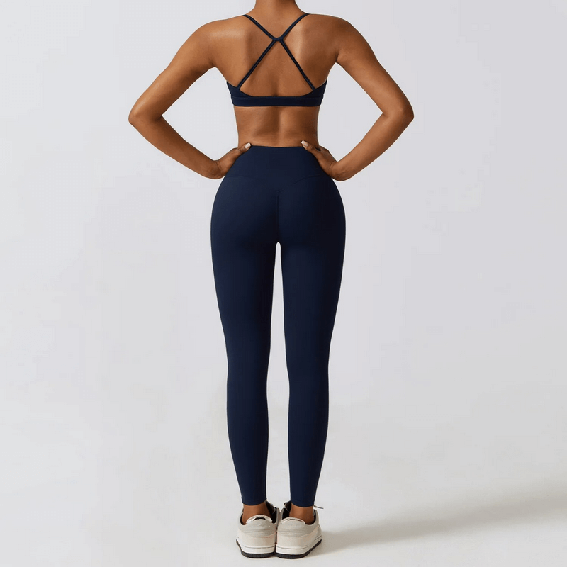 Back view of woman in navy blue 2-piece yoga set, showcasing cross-back design. Perfect for exercise and features quick-dry fabric.