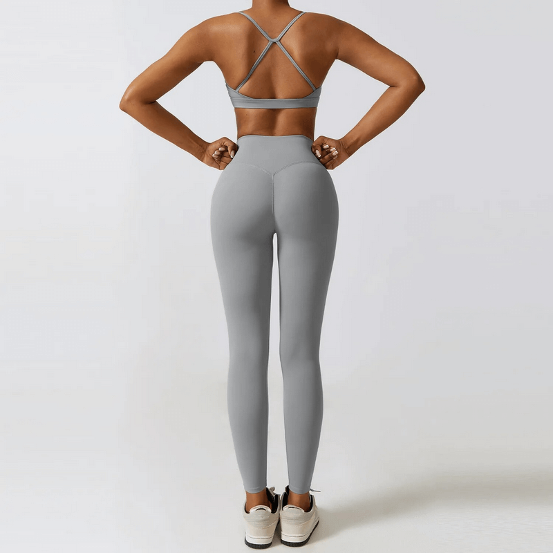 Woman wearing grey sportswear yoga set, featuring a strappy back design, ideal for activities like running and fitness. SF1691.