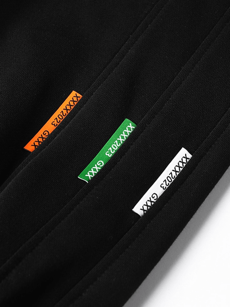 Close-up of black joggers featuring colorful label tags for sporty style.