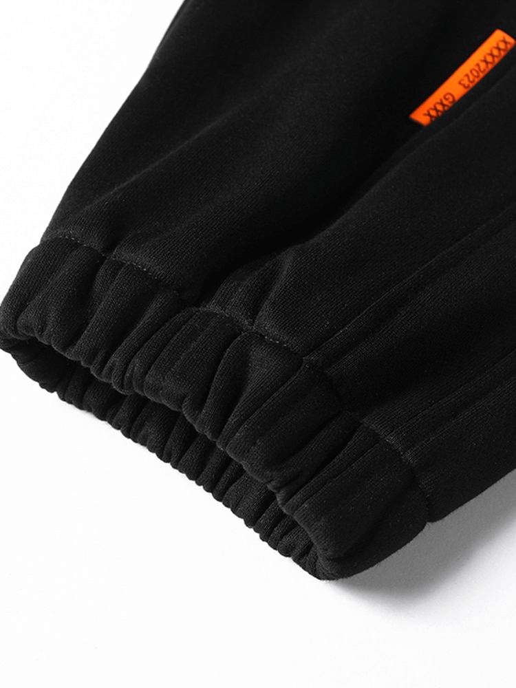 Close-up of black jogger pants cuff with elastic band, showcasing fine stitching and material texture.