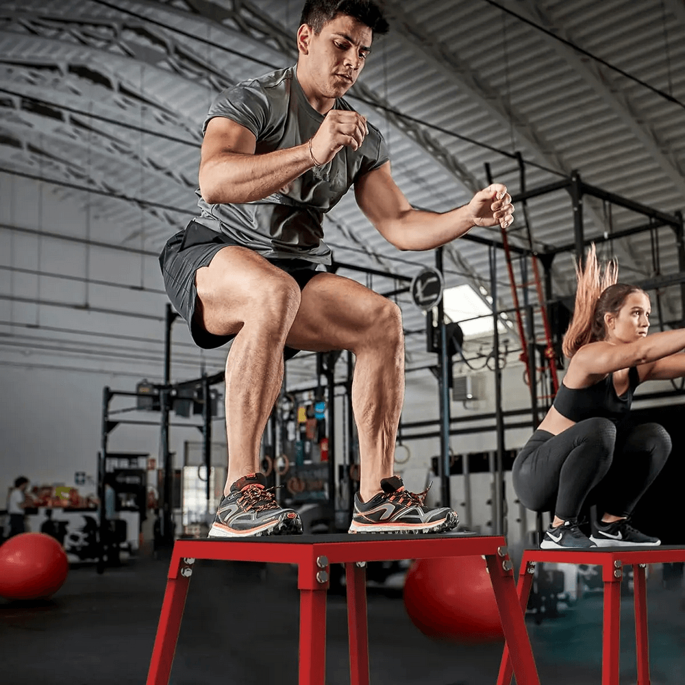 Man and woman using stackable steel plyometric jump boxes for jump training in gym, showcasing agility and fitness.