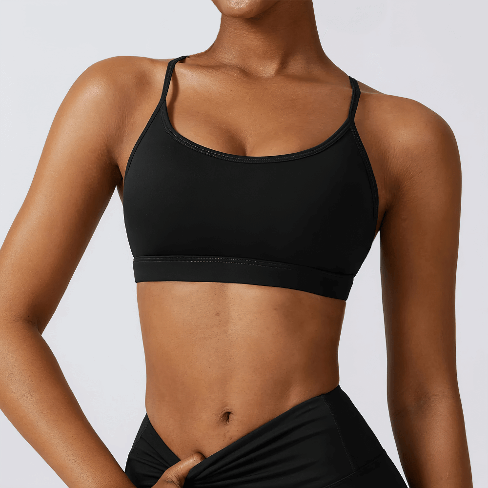 Black strappy-back sports bra, perfect for workouts and yoga, featuring a seamless design and moisture-wicking fabric.