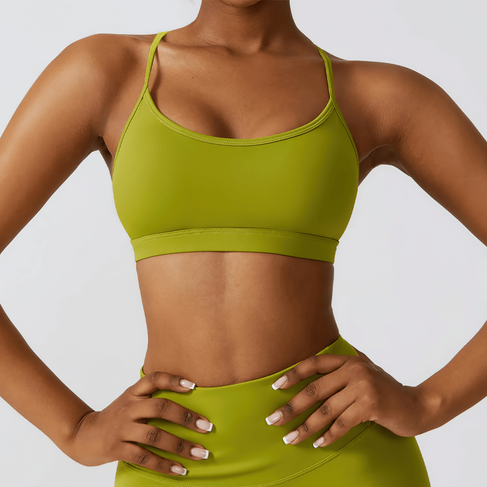 Woman wearing green strappy back sports bra, seamless workout top for fitness, yoga, or casual wear. Stylish and breathable activewear.