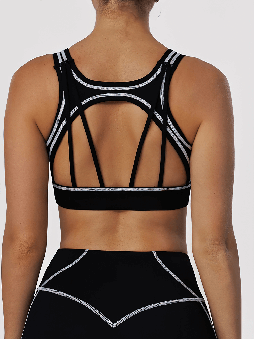 Model wearing Strappy Back Sports Bra with Removable Pads - SF4062 showcasing open multi-strap back and contrast seams.