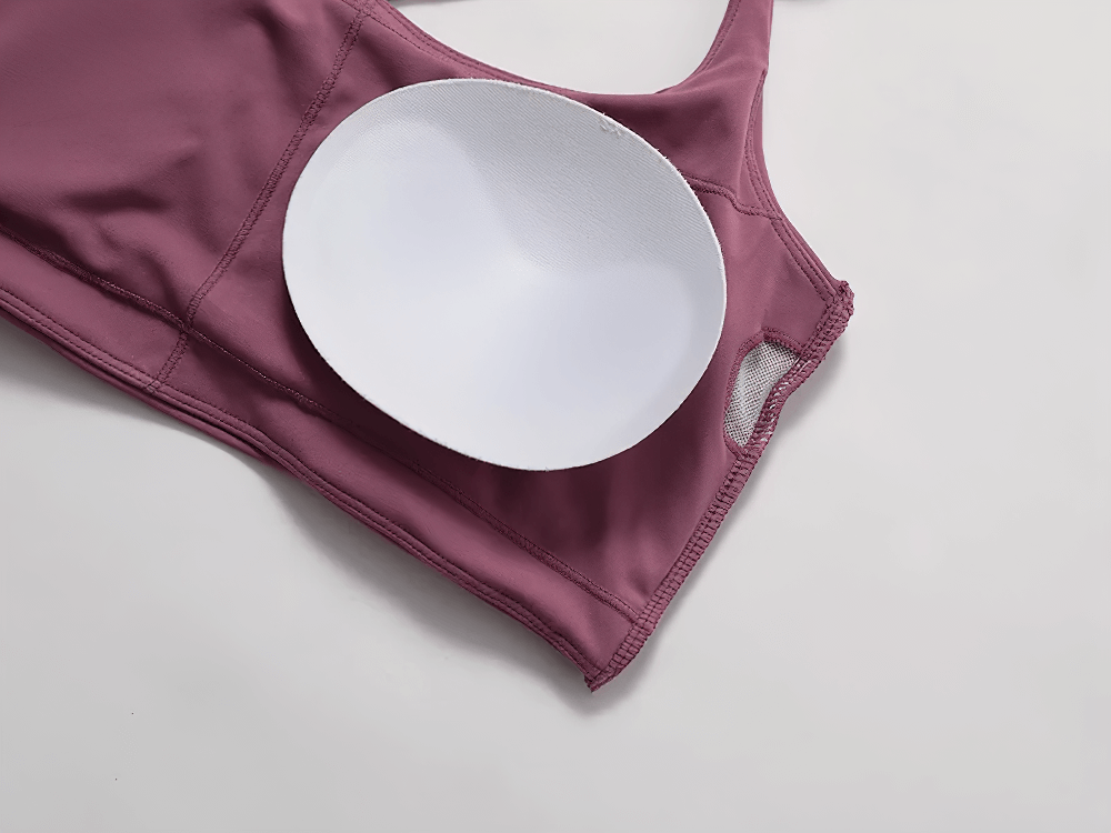 Close-up of a mauve strappy cross-back sports bra with removable padding, highlighting soft fabric and design details.