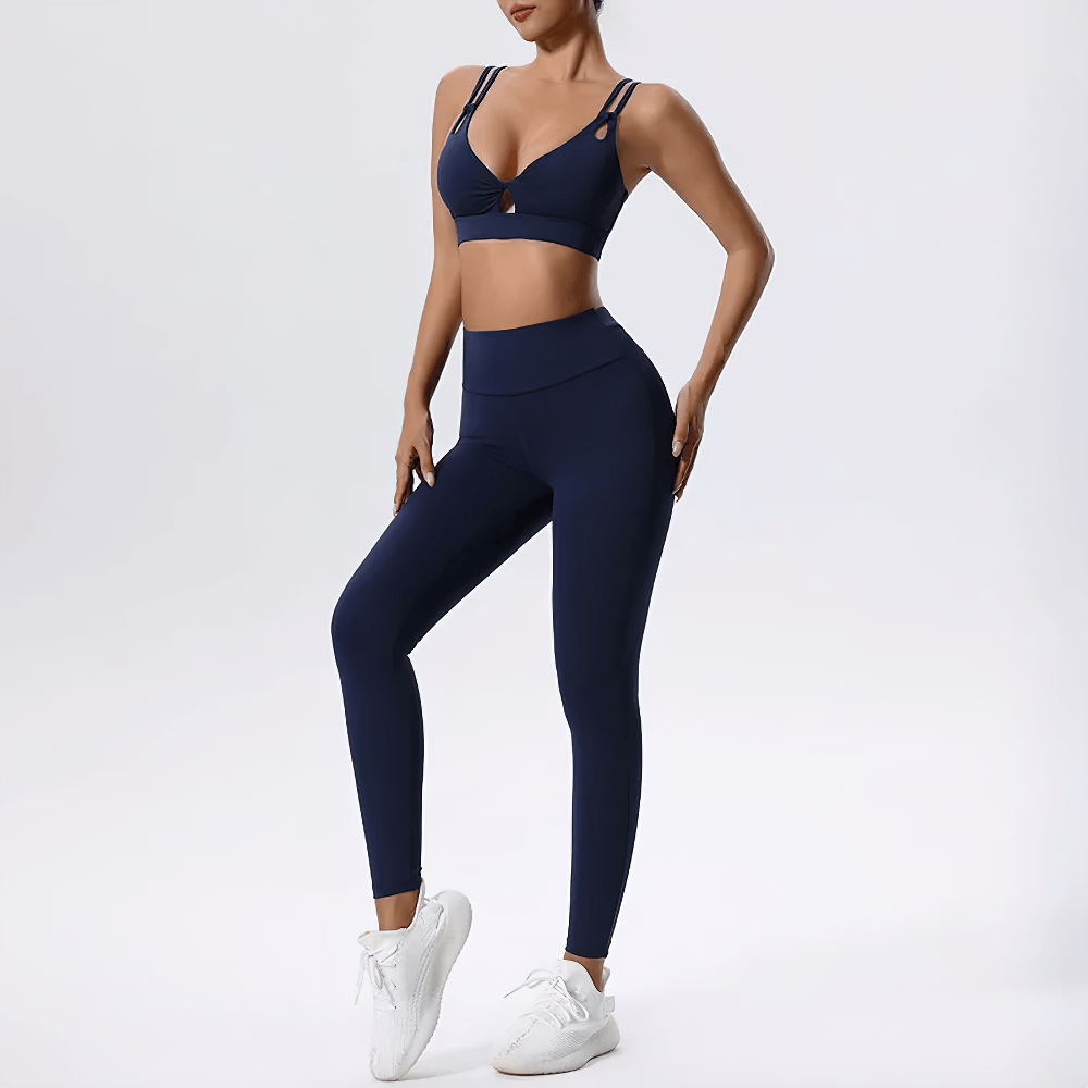 Strappy sports bra and high-waisted leggings set in navy blue, ideal for yoga and training. Featuring crisscross design for style and support.