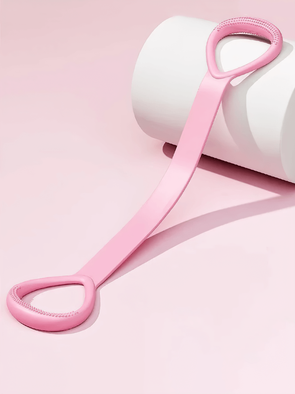 Pink stretch band for yoga and strength training with ergonomic handles on a pastel background, ideal for flexibility and posture.