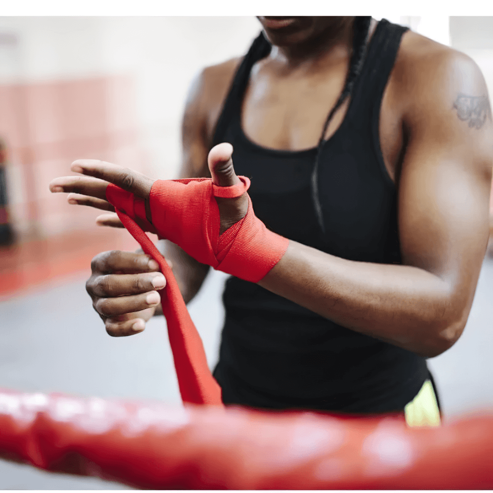 Athlete wrapping hands with stretchable red boxing hand wrap for secure wrist support during training.