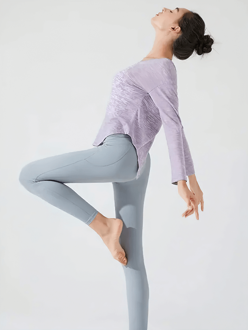 Woman in yoga pose wearing a stylish back-cutout see-through top, demonstrating flexibility and active wear design.