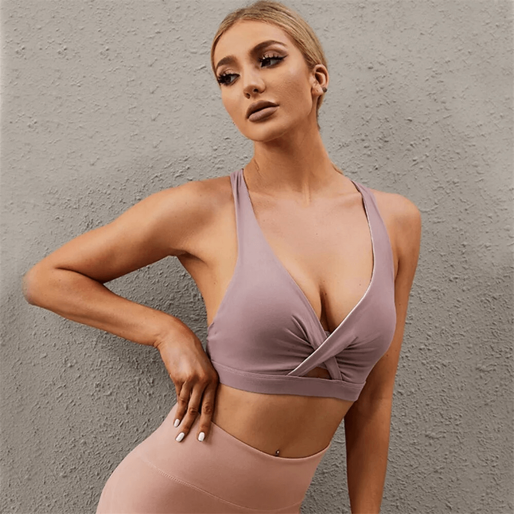 Stylish breathable women's sports bra with woven front showcased by model against gray backdrop for yoga and running.