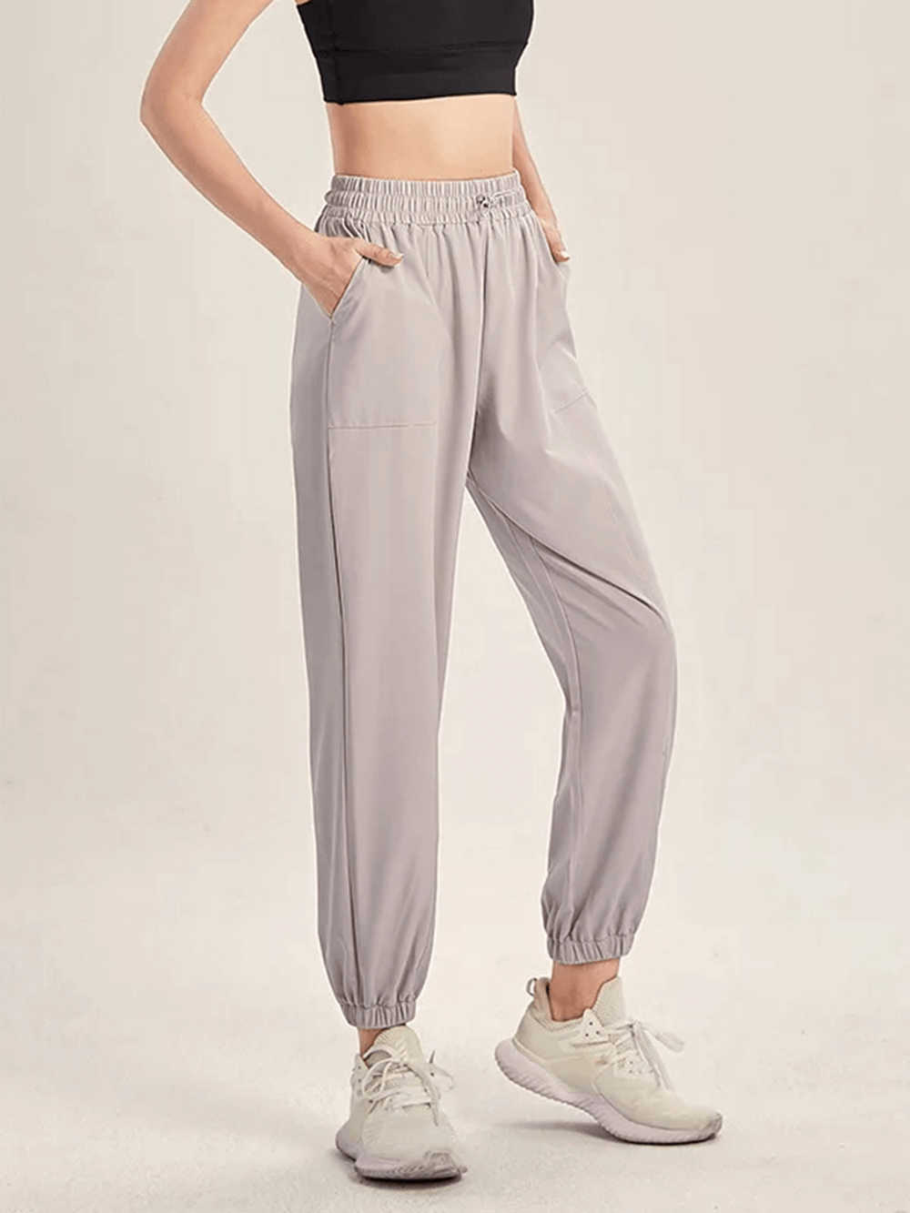 Women's gray drawstring joggers for yoga, gym, running, or dance. Durable polyester and spandex, flexible fit for athletics.