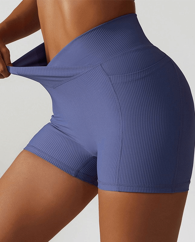 Model wearing stylish elastic women's shorts in blue, featuring side pockets, breathable fabric, and a snug fit for yoga or active wear.